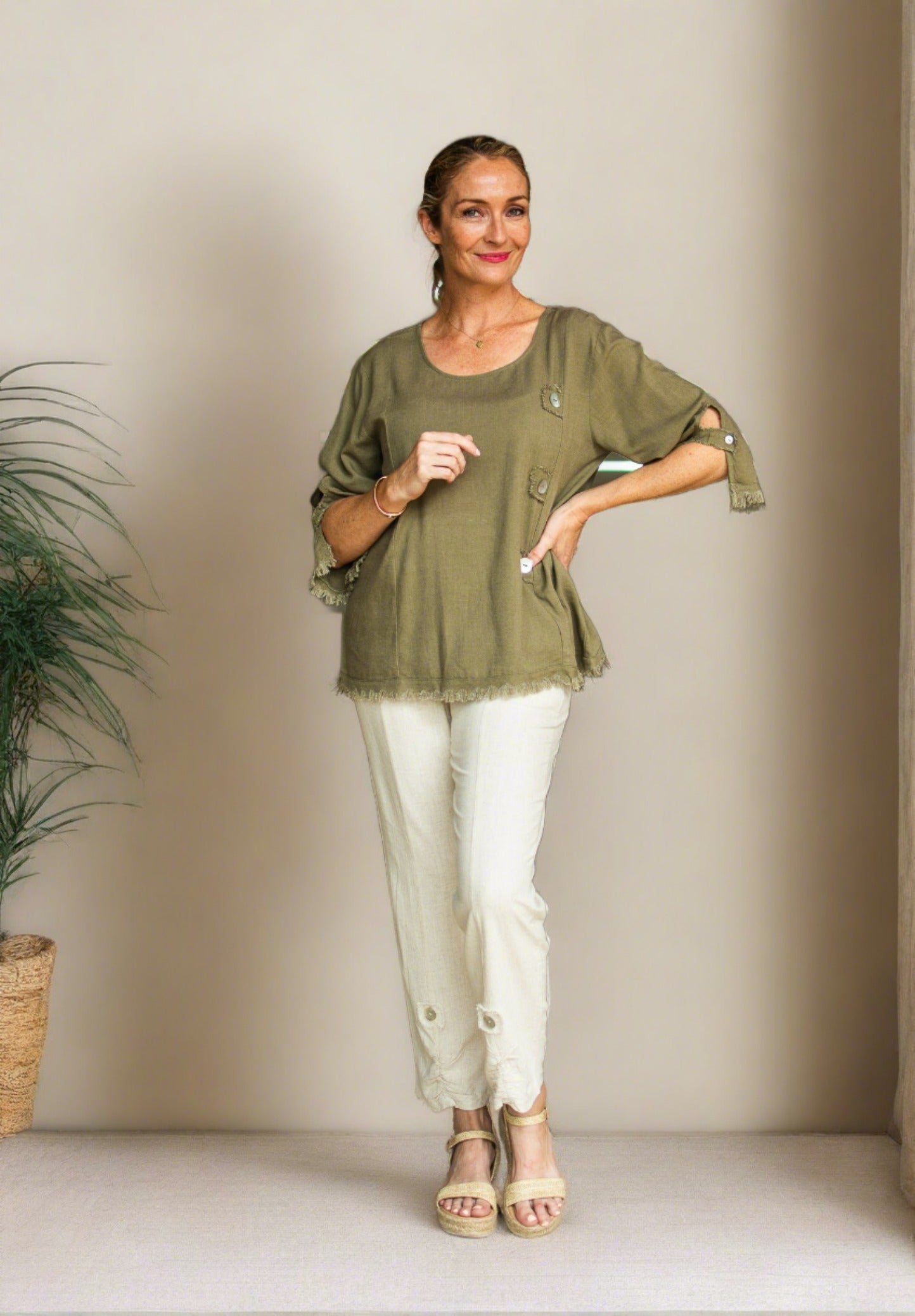 Ladies cream linen pants with button detail at bottom on front.